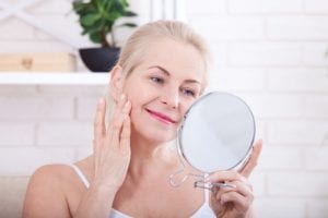 Forty years old woman looking at wrinkles in mirror