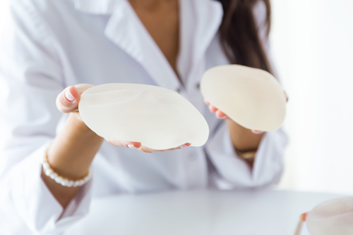 female patient looking at two types of breast augmentation implants- img-blog