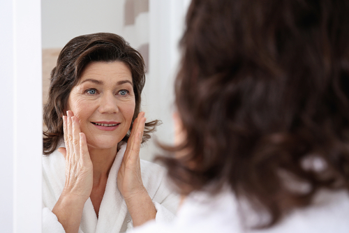 senior woman touching face in front of mirror-img-blog