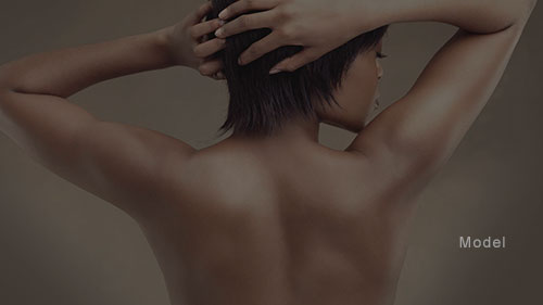 Back view of a woman with sculpted arms with her hands over her head
