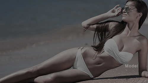 Thin woman in a white bikini and sunglasses laying on the sands of a beach