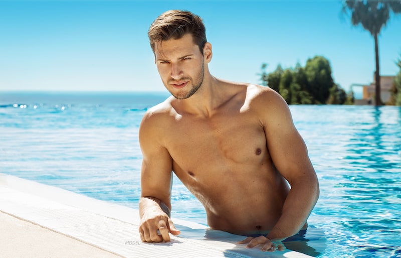 Attractive shirtless man standing in the pool
