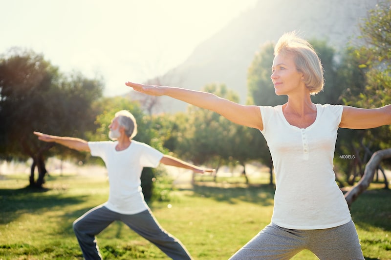 Mature couple doing yoga outside. 