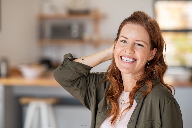 Woman smiling as she brushes her hand through her hair