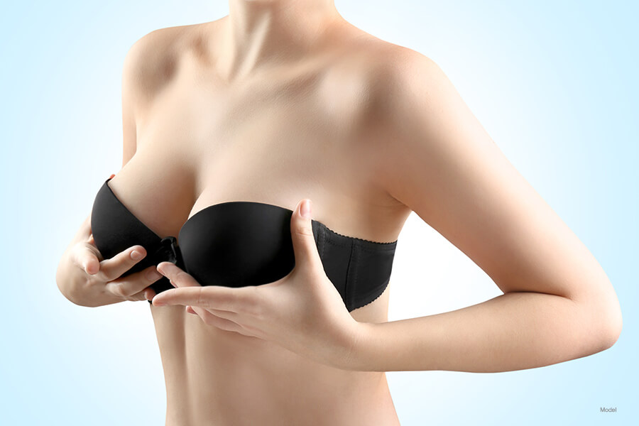 woman in black strapless bra holds up breasts