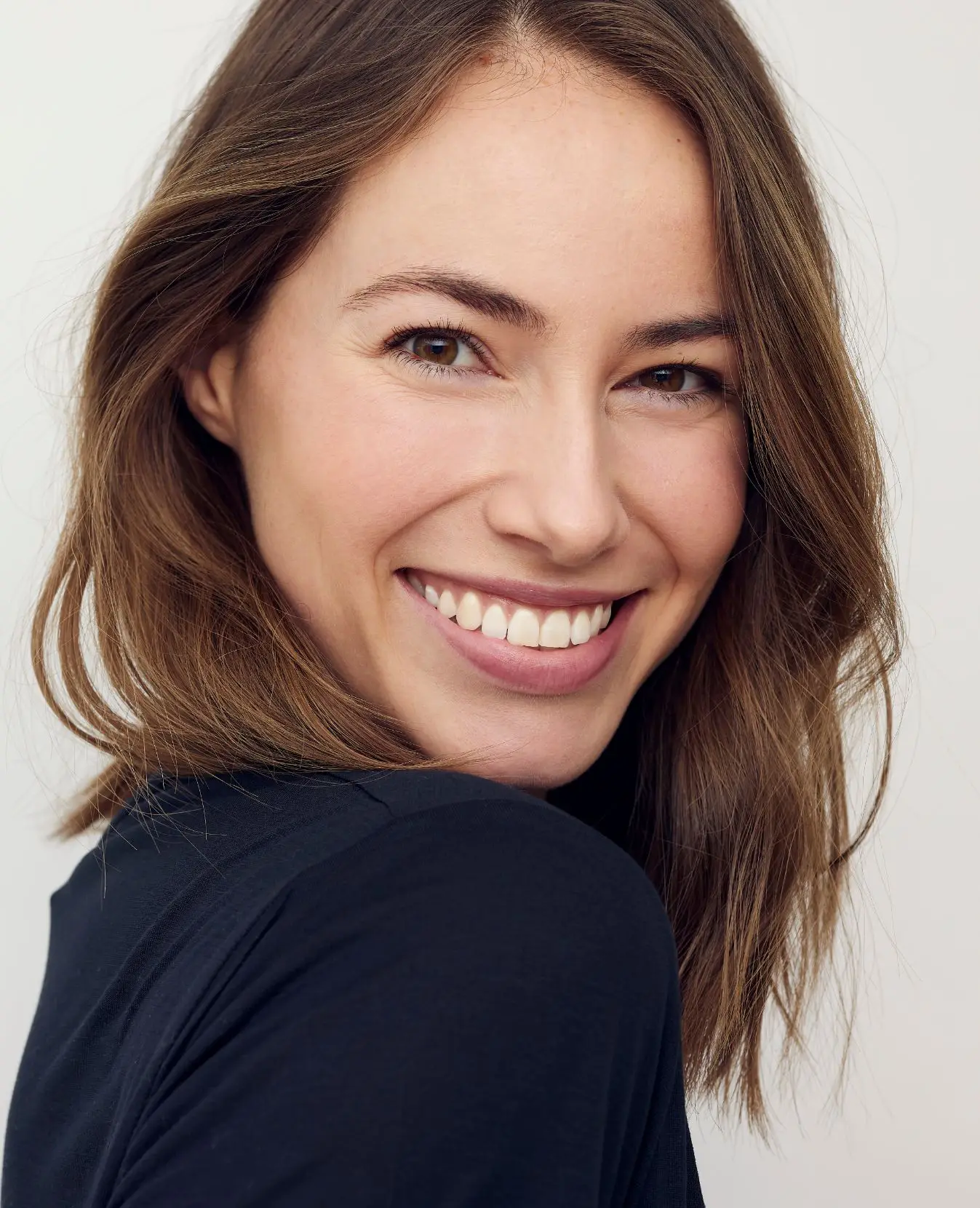 Woman with a blue turtle neck and smiling