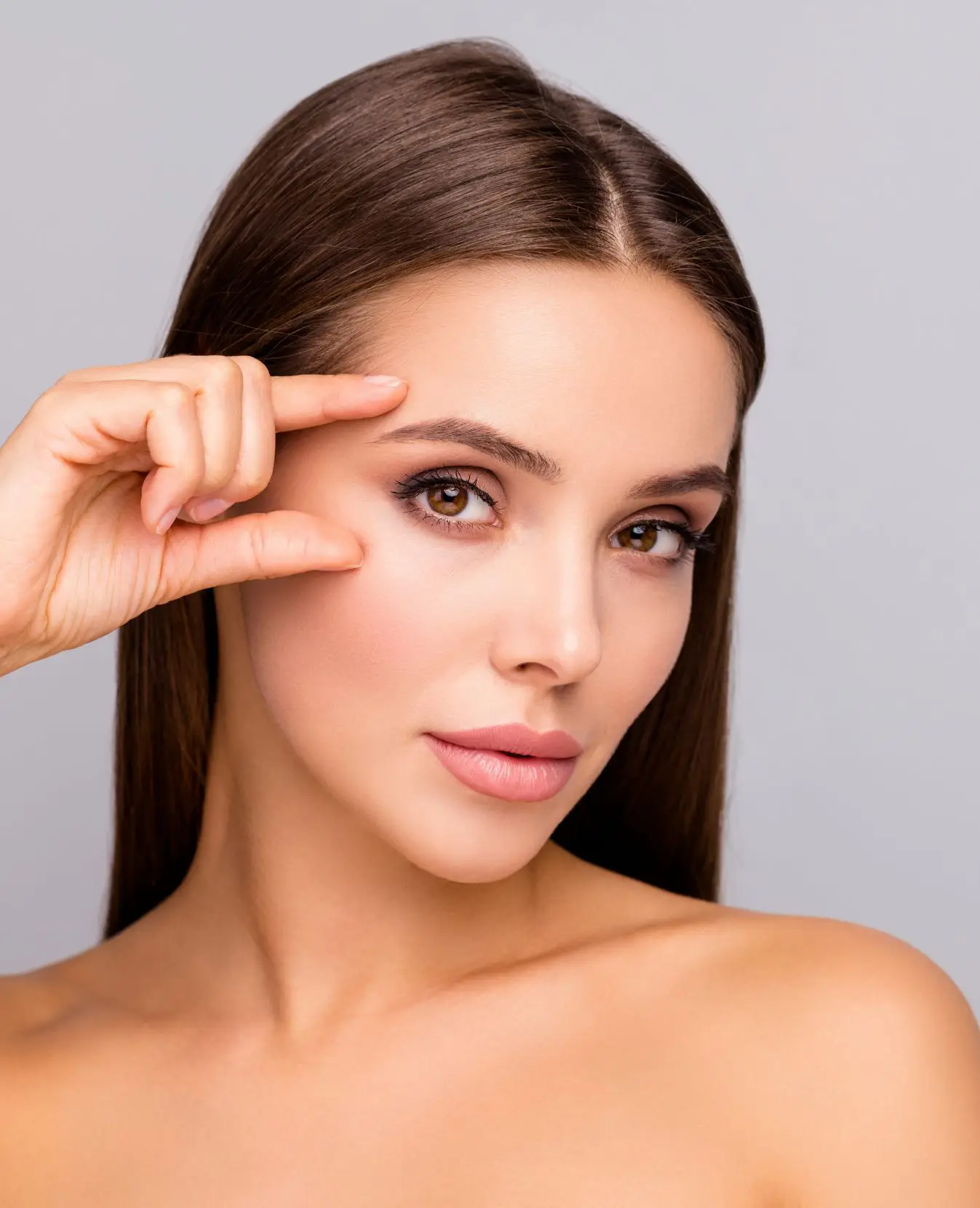 Woman holding two fingers along her eye line