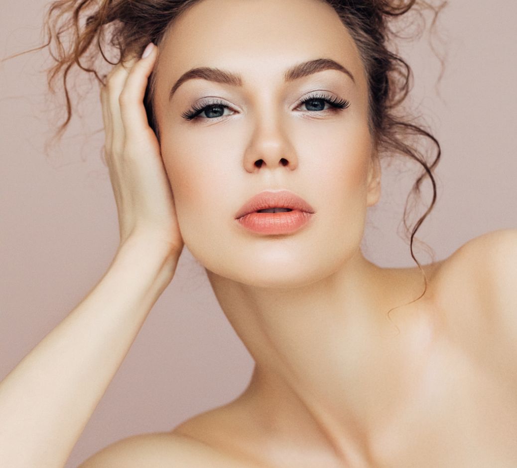 woman against a light pink background with smooth skin